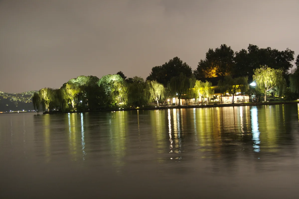 West Lake trees and shoreline reflections at night in Hangzhou