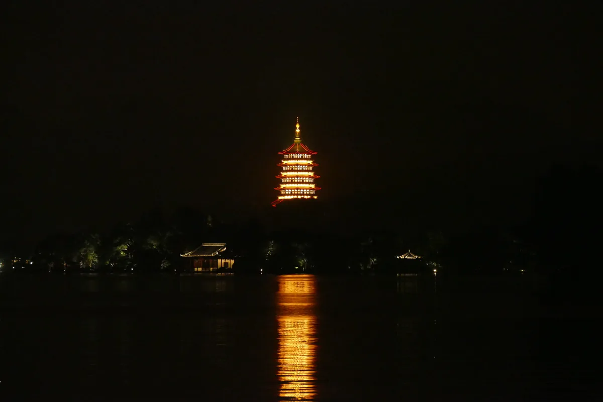 Leifeng Pagoda illuminated at night beside West Lake