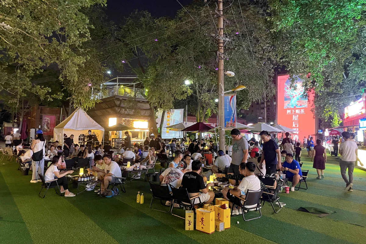 Visitors sitting among stalls at Zhengzhou Oil Chemistry Factory night market