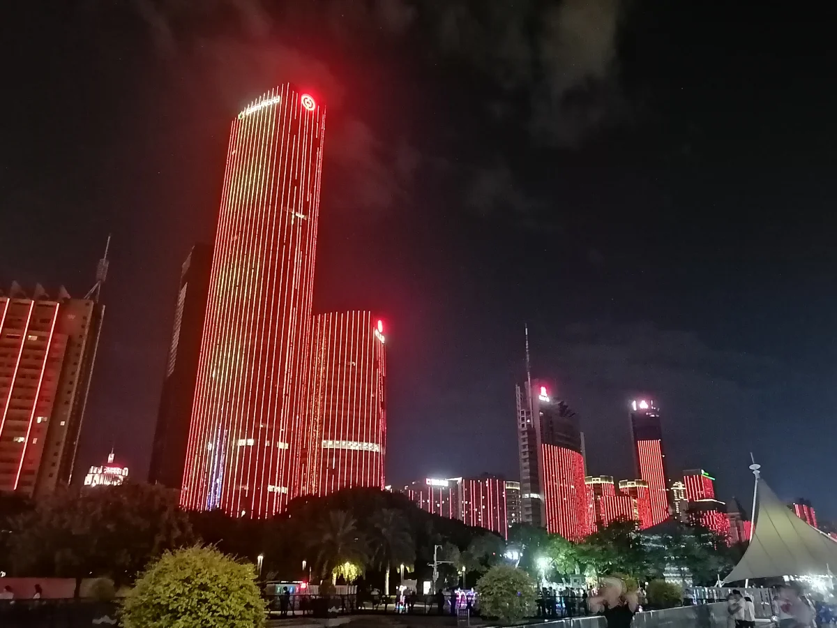 Red-lit skyscraper and surrounding towers in Honggutan at night