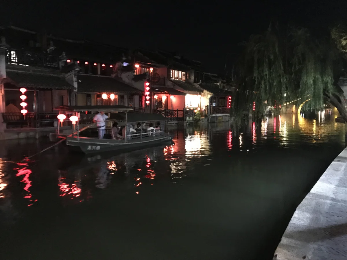Boat passing lantern-lit houses on a Xitang canal at night