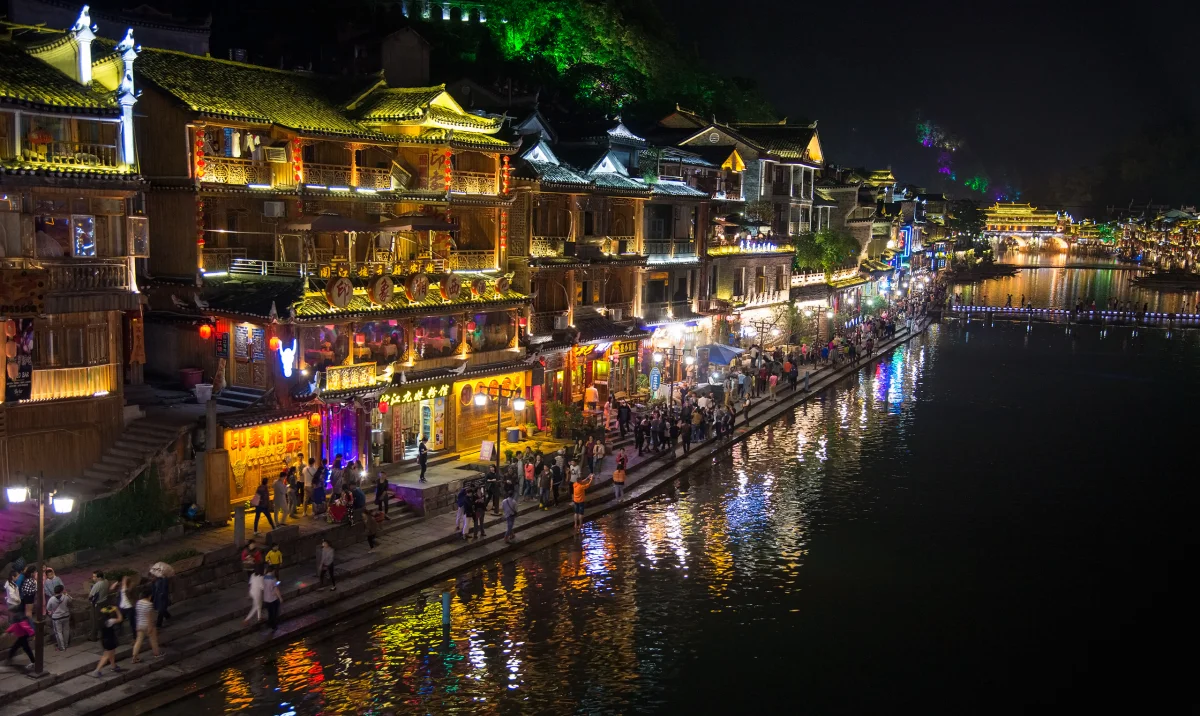 Lit balconies and visitors along the Tuojiang riverbank