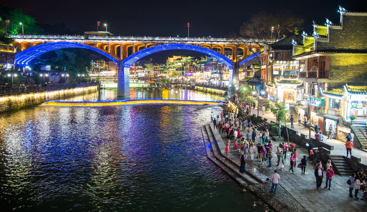 A blue-lit bridge above the curved Tuojiang promenade