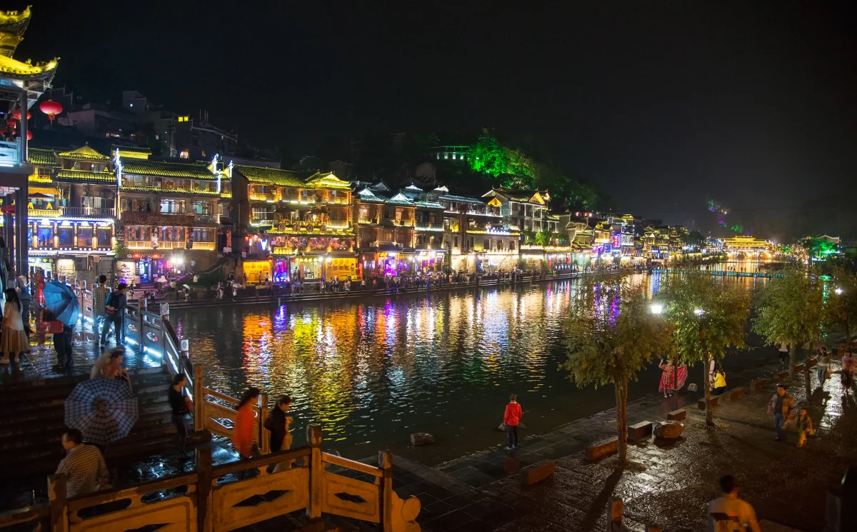 Visitors on a low crossing below Fenghuang riverside houses