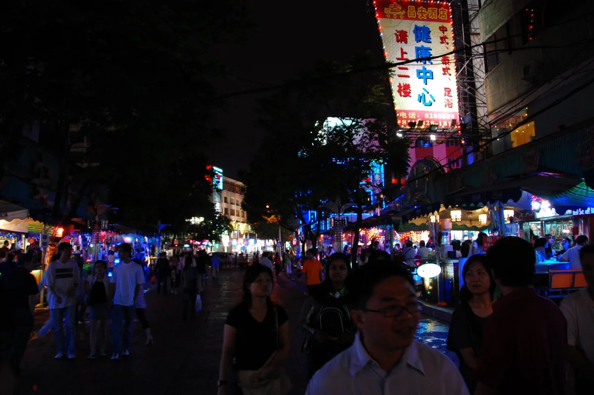 Visitors and shop signs along Lotus Road in Zhuhai at night